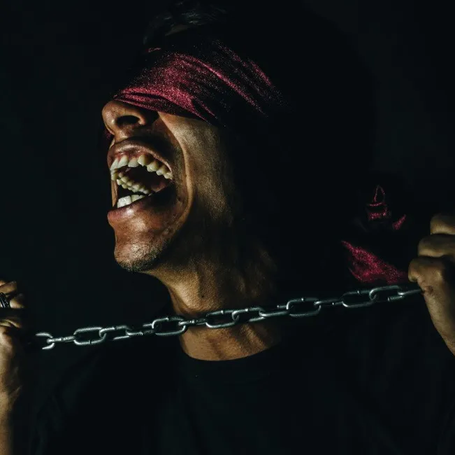 A blindfolded person pulling against a chain