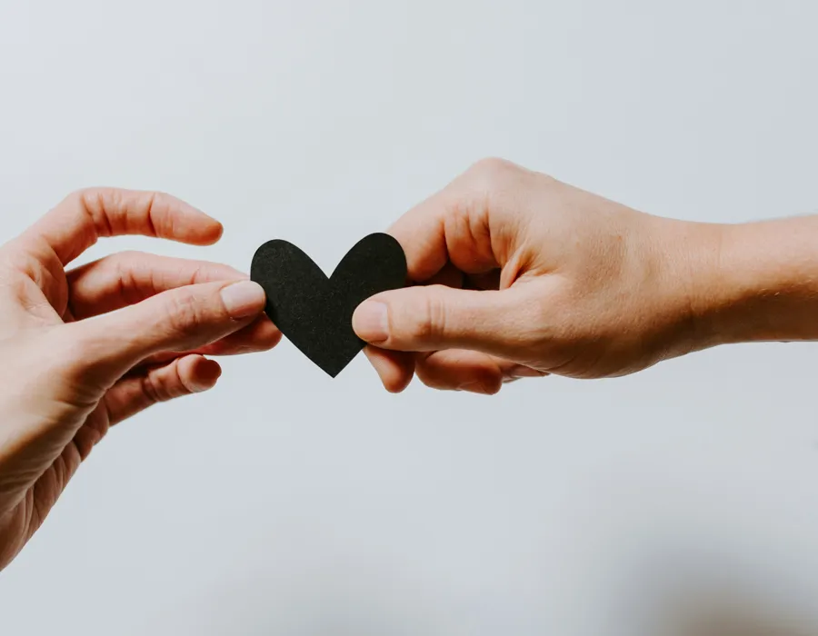 Two hands passing a small heart