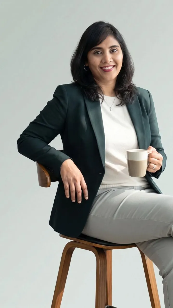 Ash Pesala seated, holding a cup